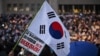 A protester holds the South Korea flag during a candlelight rally calling for the ouster of South Korea President Yoon Suk Yeol at the National Assembly in Seoul on December 5, 2024.