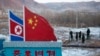 FILE - Chinese paramilitary police build a fence near a concrete marker depicting the North Korean and Chinese national flags with the words "China North Korea Border," at a crossing in Tumen, China, Dec. 8, 2012.