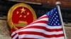 FILE - An American flag is flown next to the Chinese national emblem during a welcome ceremony at the Great Hall of the People in Beijing, Nov. 9, 2017. 