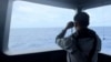 In this undated photo released Oct. 24, 2024 by the Indonesian Maritime Security Agency, a sailor monitors the movement of a a Chinese coast guard vessel in the water of North Natuna Sea in the disputed area of the South China Sea.