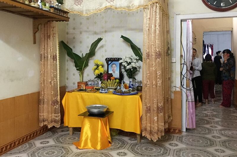 A framed portrait of Pham Thi Tra My sits on a table laden with gifts and a golden cloth.