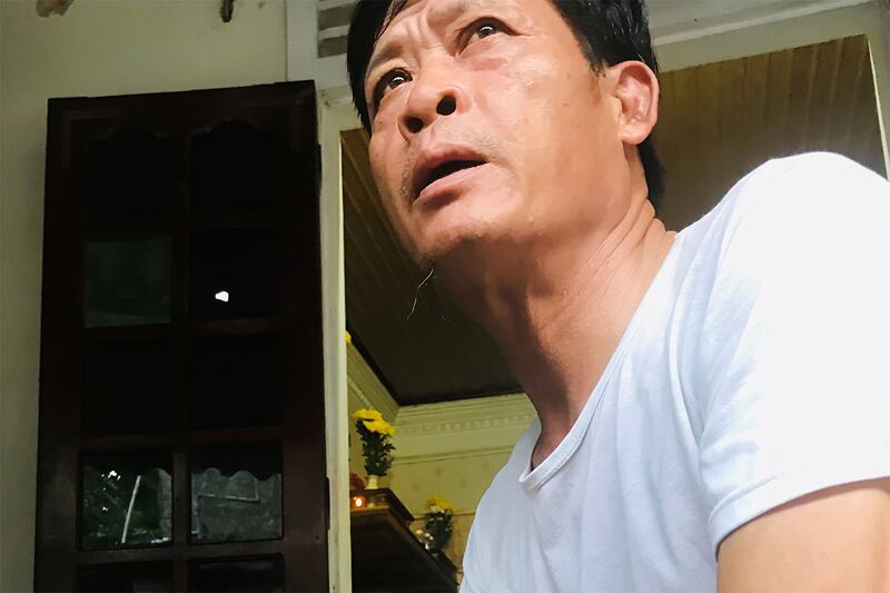 Pham Van Thin, a middle-aged Vietnamese man, looks up and to the right with an expression of sorrow. He is wearing a white t-shirt.