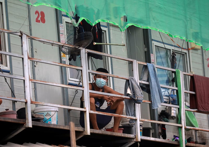 A Myanmar migrant worker passes the time on his balcony in a workers\' dormitory in Bangkok, May 22, 2021.