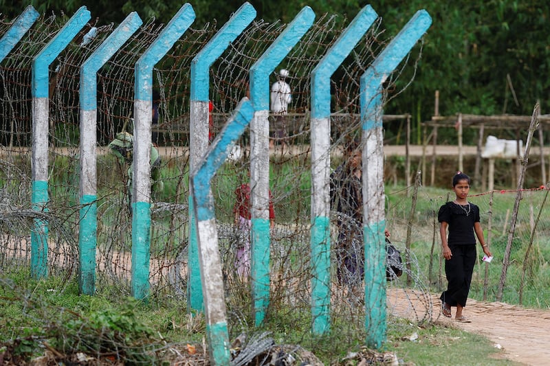 A Rohingya refugee walks past a camp border fence in Cox\'s Bazar, Bangladesh, Sept. 28, 2024.