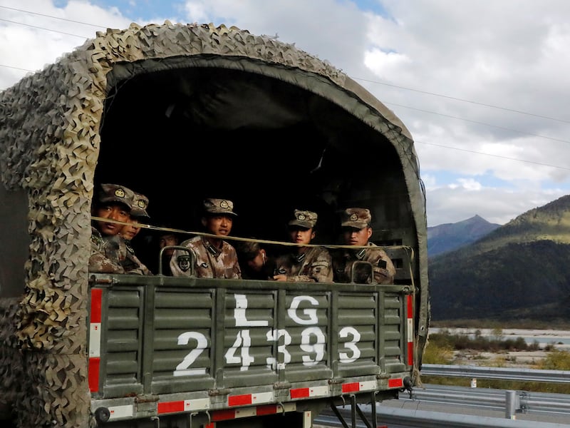 Chinese soldiers of the People\'s Liberation Army sit on the back of a truck on the highway to Nyingchi, Tibet Autonomous Region, China, October 19, 2020)