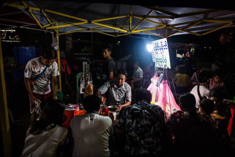 People eat at a roadside food stall during an electricity blackout in Yangon on April 26, 2024.