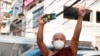 FILE - A Buddhist monk flashes a three-fingered salute and holds a smart phone during a protest in Yangon, Myanmar, Feb. 7, 2021. Myanmar’s military government is now blocking VPNs, which help internet users bypass restrictions to access websites and social media. 