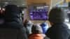 People watch a TV screen showing news coverage of a mob loyal to US President Donald Trump storming the US Capitol, at the Seoul Railway Station in Seoul, South Korea, Jan. 7, 2021.